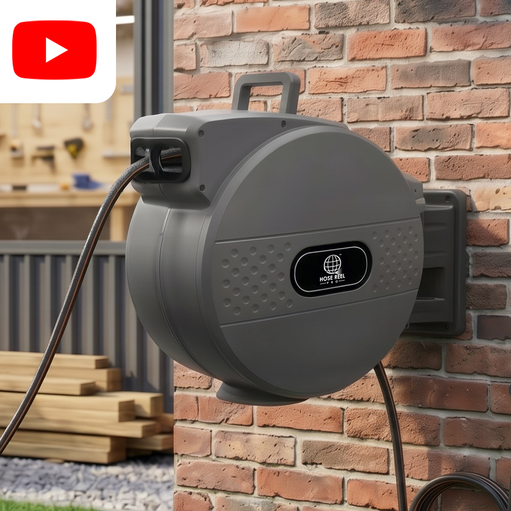 Gray wall-mounted hose reel with a thick black hose, attached to a brick exterior near a workshop area.
